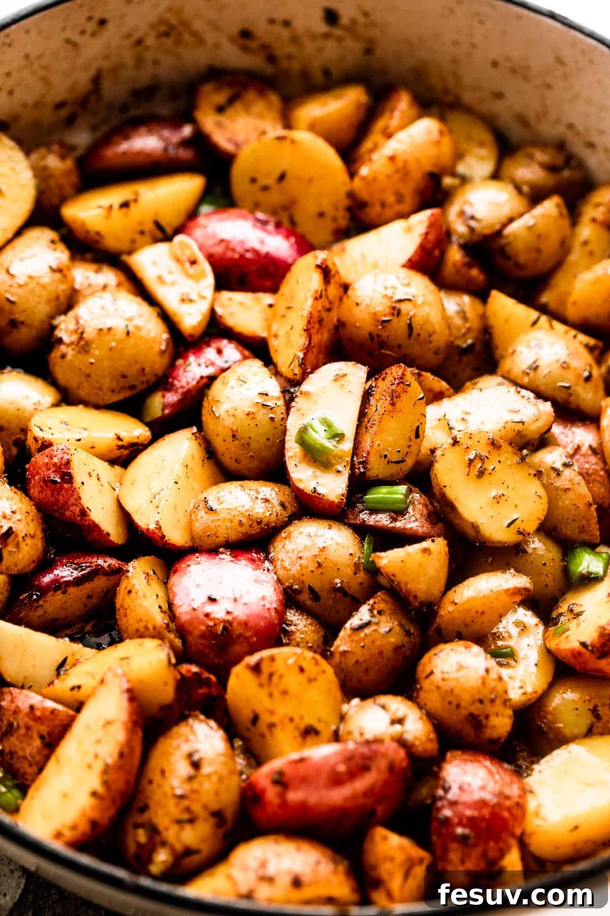 Golden Roasted Potatoes with Bacon and Cheese 4 quartered small potatoes in a white skillet.