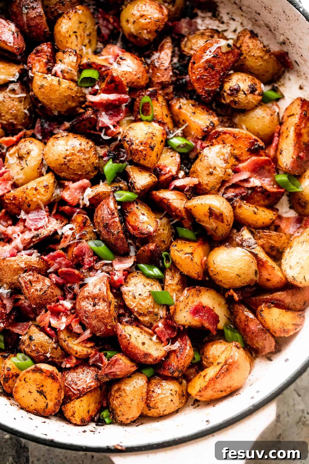 Golden Roasted Potatoes with Bacon and Cheese 5 overhead shot of roasted potatoes and bacon in a white skillet.