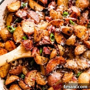overhead shot of roasted potatoes and bacon in a white skillet.