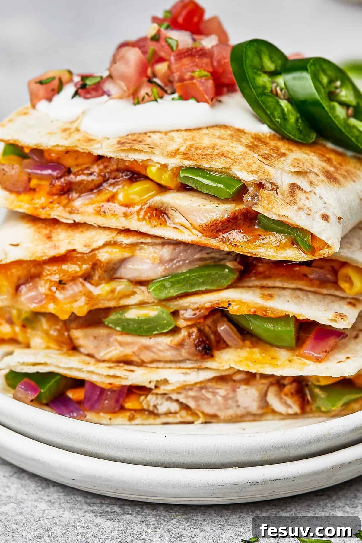 Chicken quesadillas stacked on a plate, viewed from the side to show texture.
