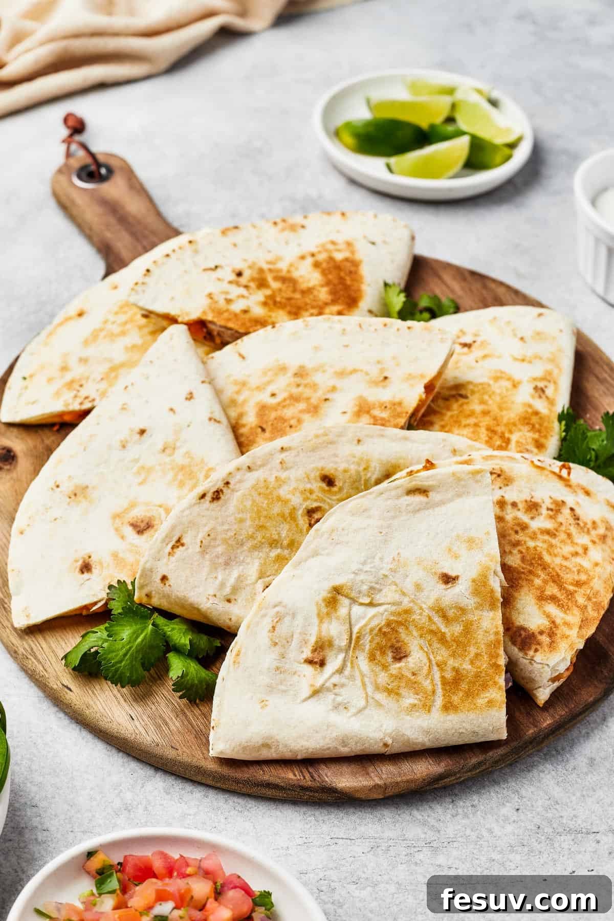 Tortilla wedges fanned out on a wooden board, with jalapeno garnish.