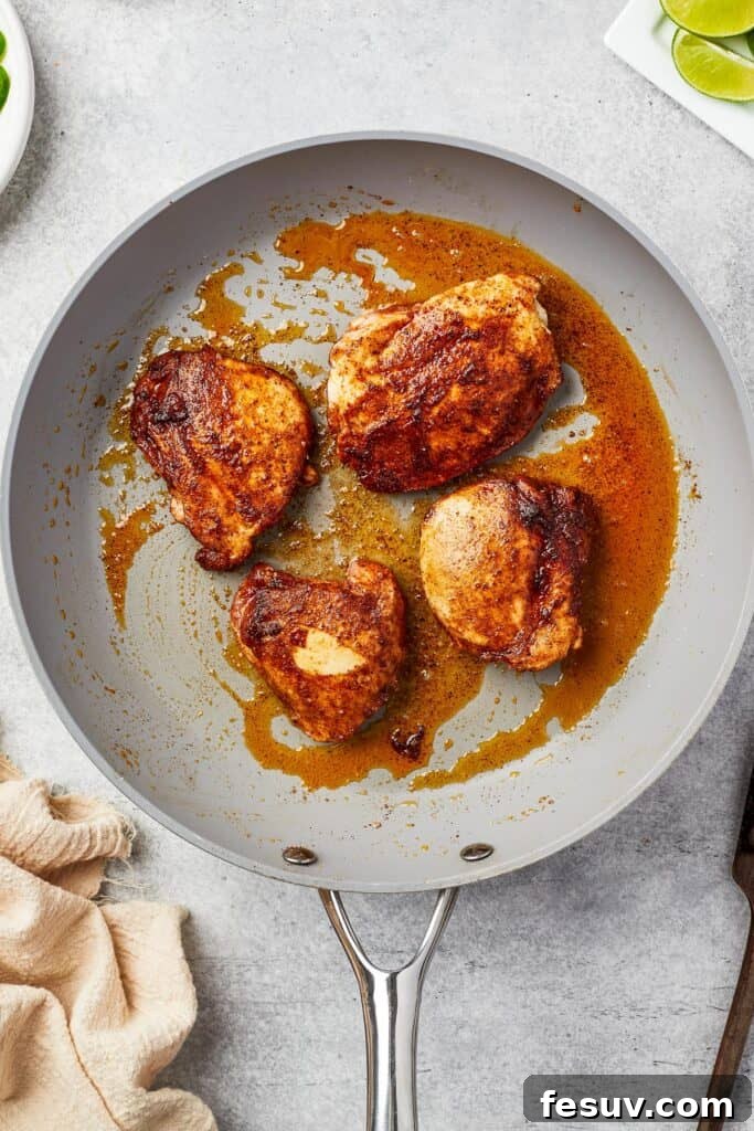 Chicken thighs cooking in a skillet.