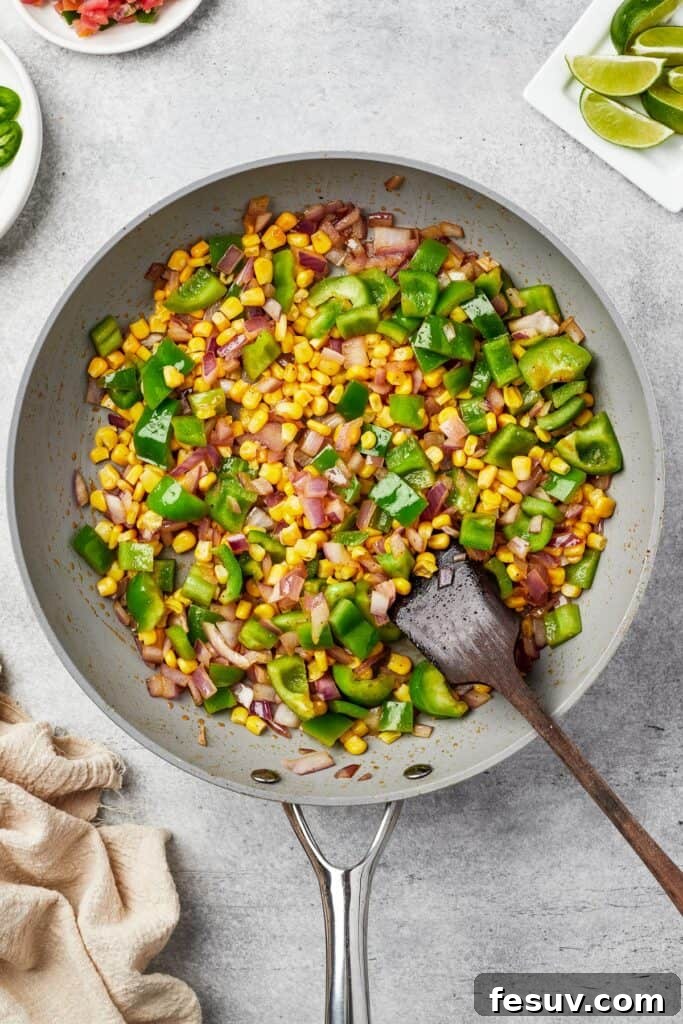 Corn, bell pepper, and onion cooking in a skillet.