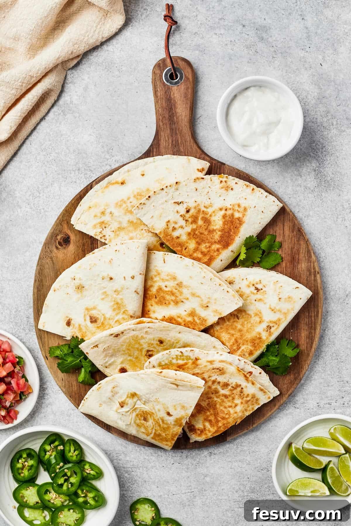 Tortilla wedges fanned out on a wooden board, with jalapeno garnish.
