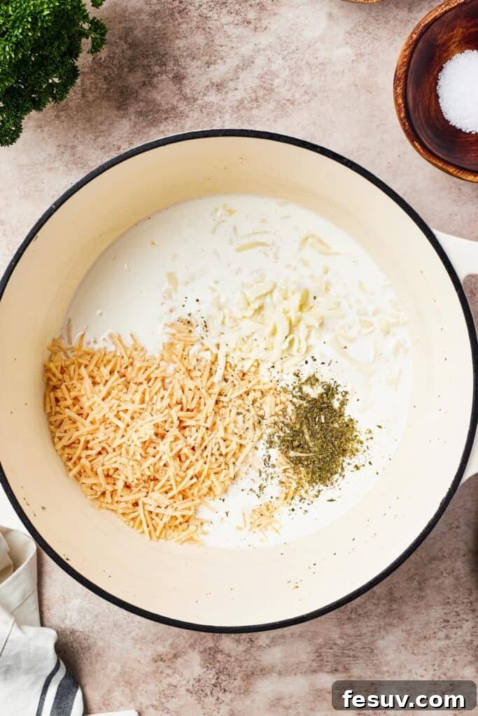 Alfredo sauce being whisked in a large pot.