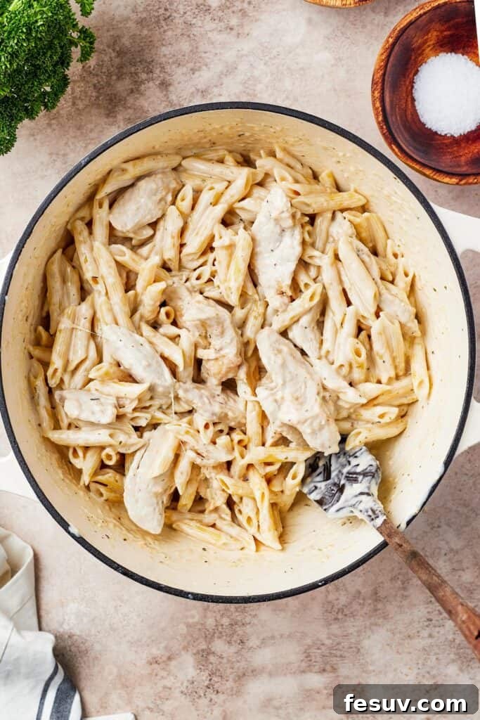 Chicken, pasta, and sauce in a large pot.