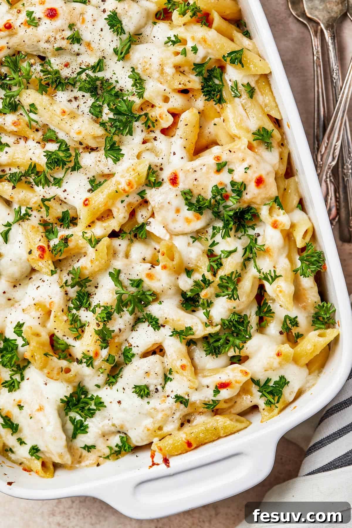 A baked chicken and pasta casserole, generously garnished with parsley.
