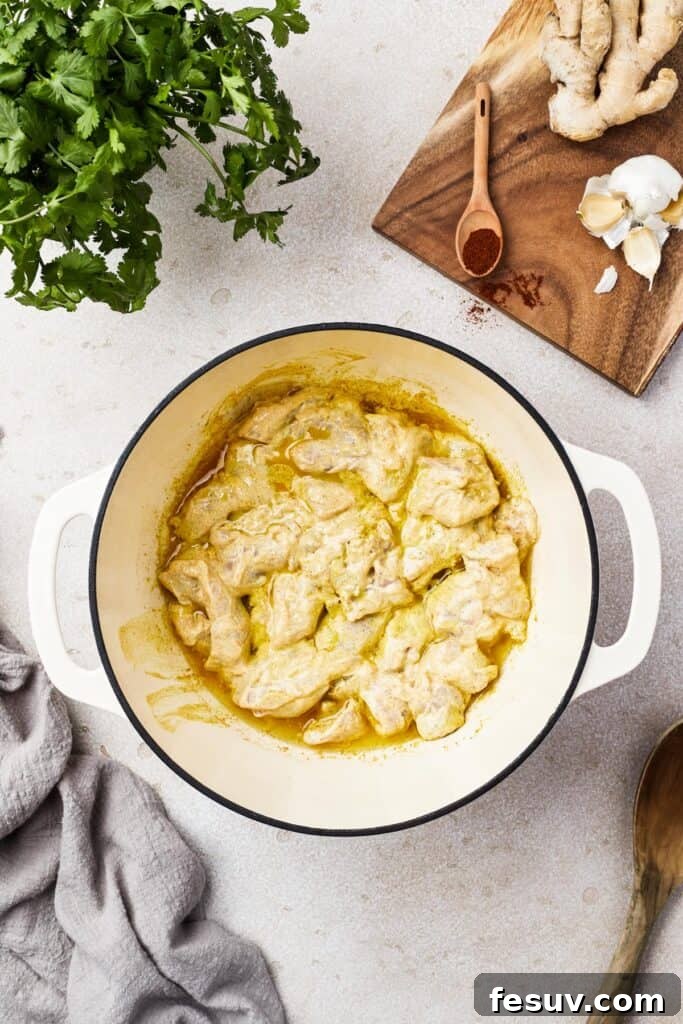 Chicken cooking in a yellow, creamy sauce.