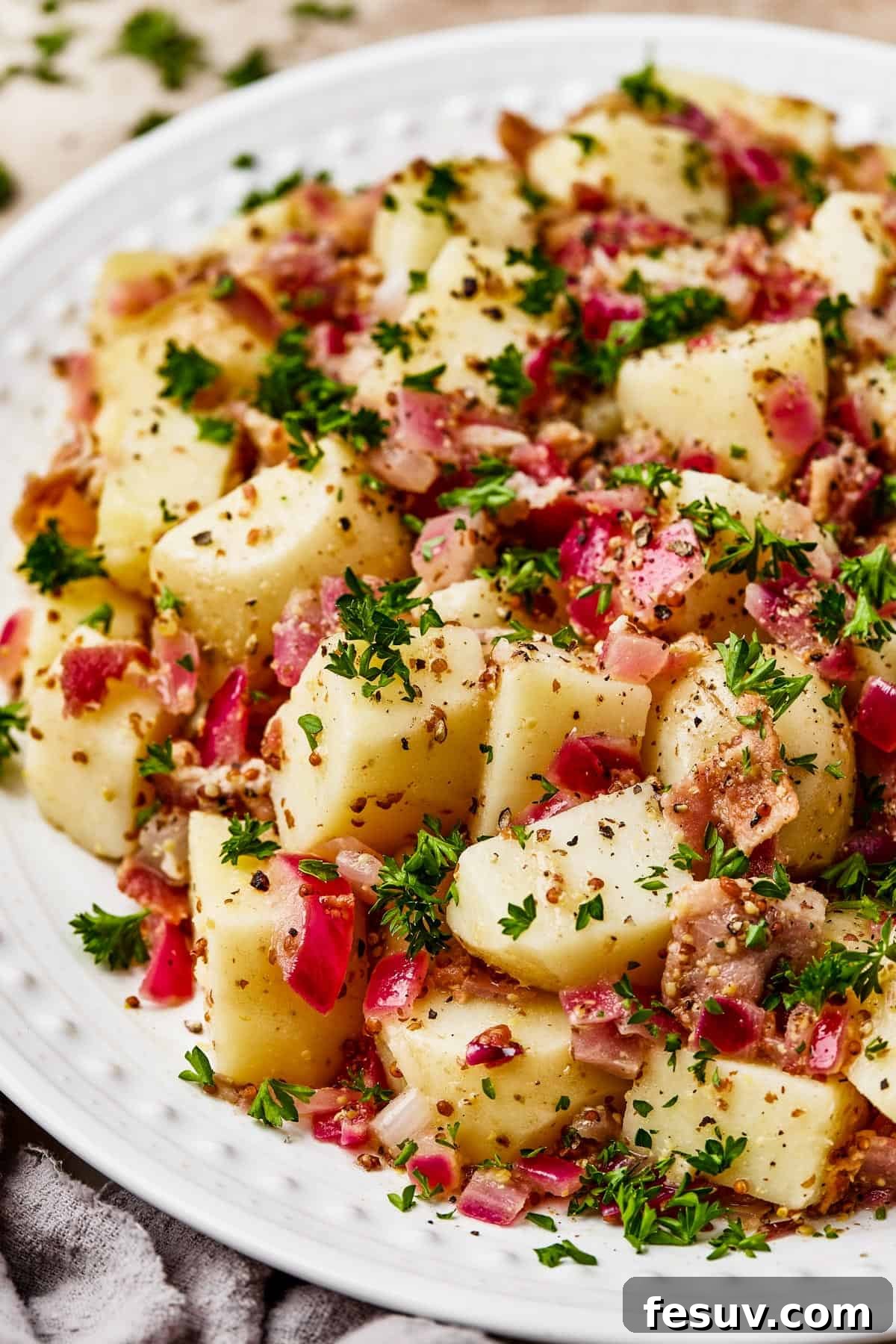 Close-up shot of chopped, boiled potatoes tossed with bacon and dressing.