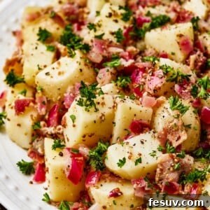 Close-up shot of chopped, boiled potatoes tossed with bacon and dressing.