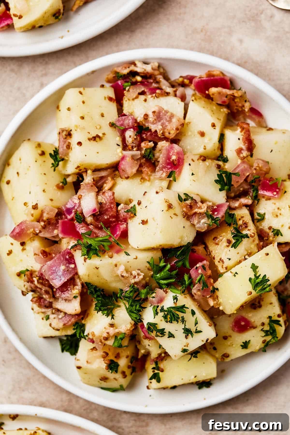 Overhead shot of several small plates, each with a serving of potatoes in bacon dressing.