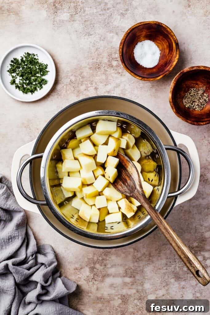 Potatoes boiling in a large pot. Dishes of parsley, salt, and pepper are arranged on the work surface.