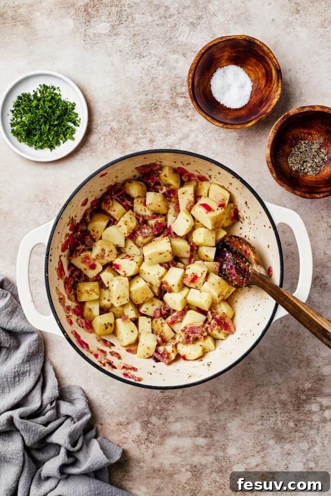Potatoes mixed with bacon and other ingredients in a large pot.