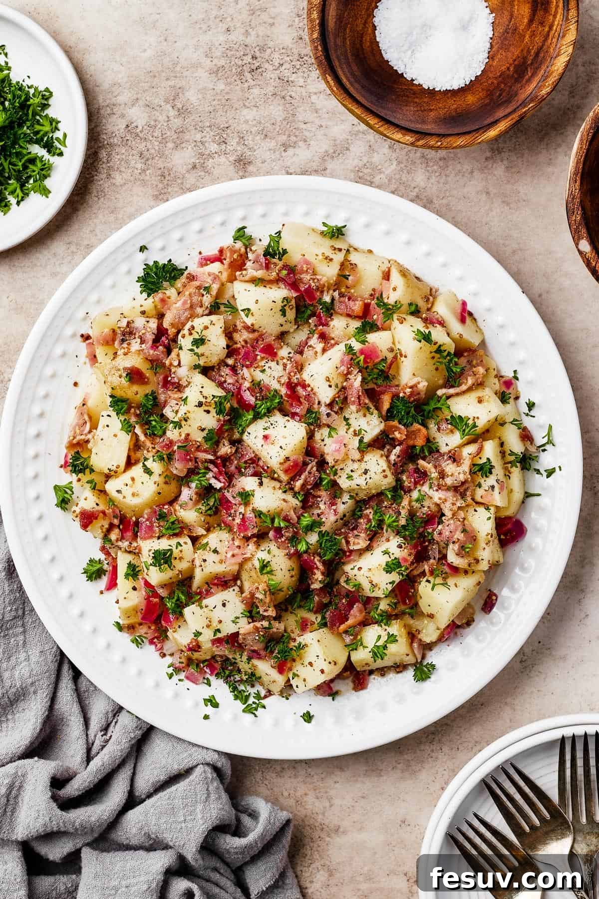 A plate of warm potato salad with herbs and bacon.