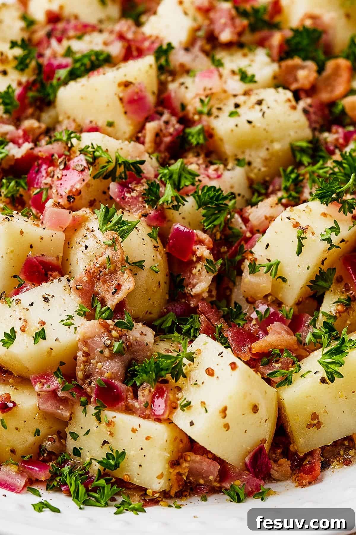 Close-up shot of potato salad on a white serving dish.