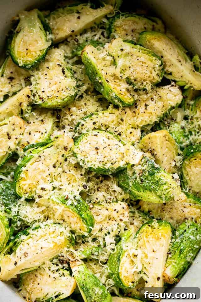 A close-up of slow-cooked Brussels sprouts generously topped with shredded Parmesan cheese.