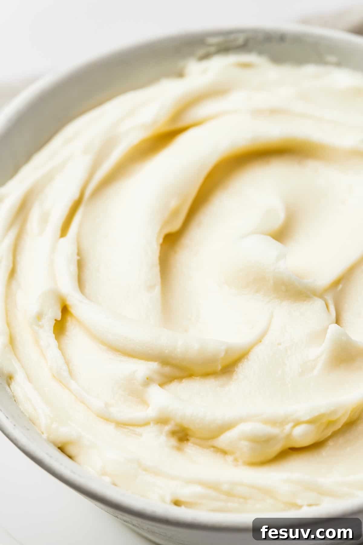 Close-up shot of white frosting, swirled in a large bowl.