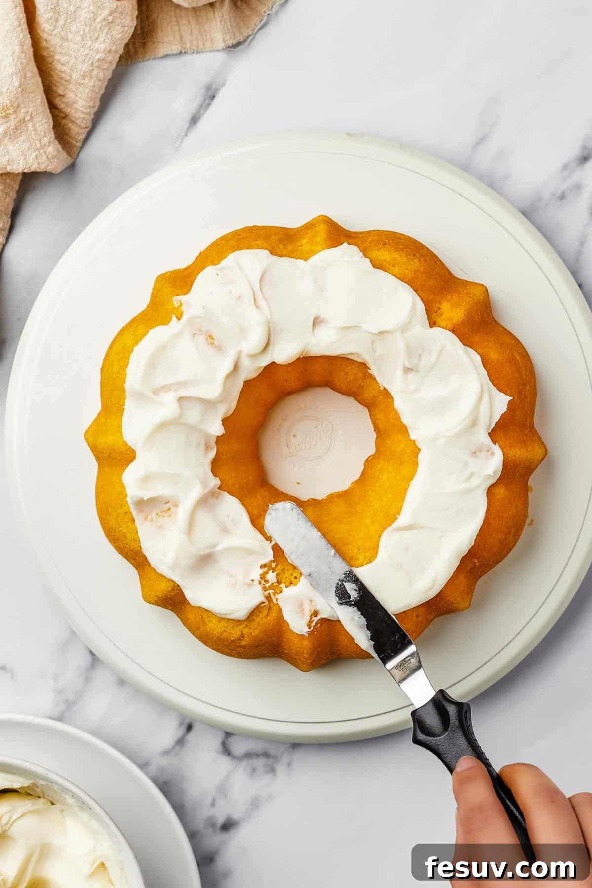 Overhead shot of a bundt cake iced with thick, creamy frosting.