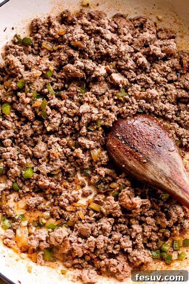 Ground beef browning in a large, hot skillet, ready for the next steps of the sloppy joe recipe.