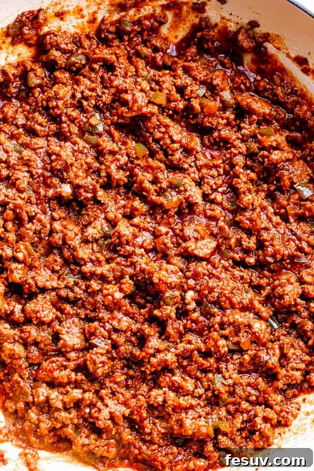 Close up of delicious sloppy joe meat simmering in a skillet, rich with tomato, brown sugar, and savory seasonings.