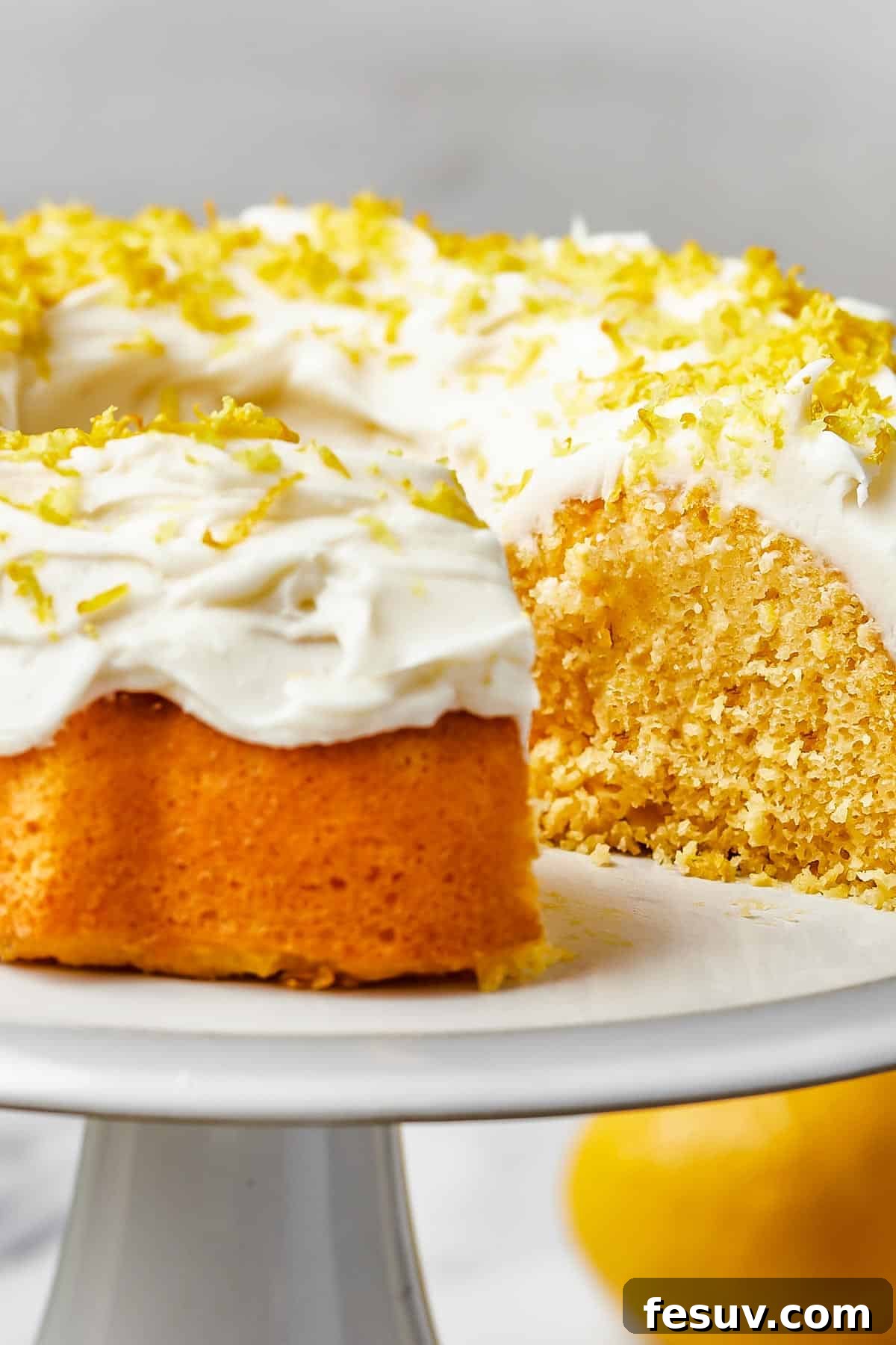 Zesty Lemon Bundt Delight 2 close up shot of a bundt cake iced with thick, creamy frosting and topped with lemon zest.
