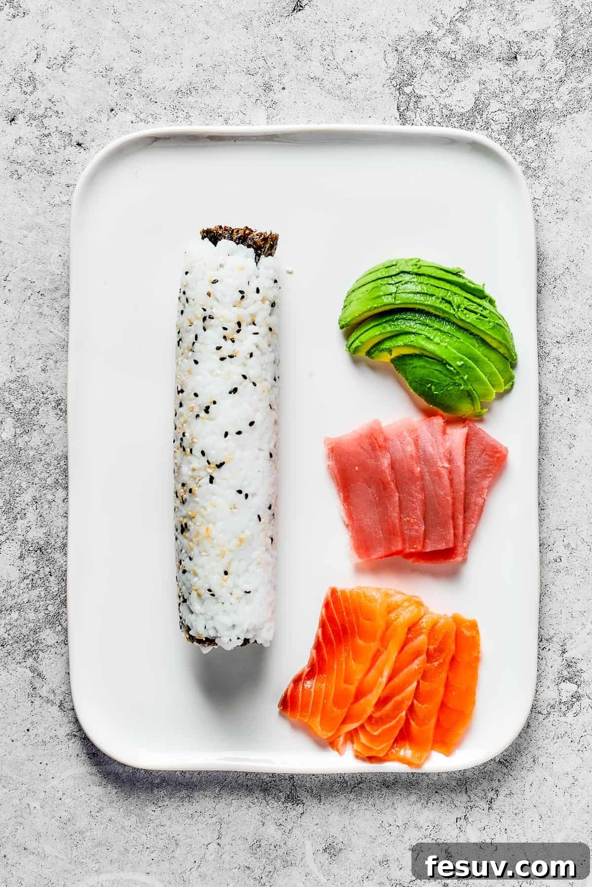 Rainbow Sushi Masterpiece 9 A platter with rolled sushi and toppings of avocado, tuna, and salmon.