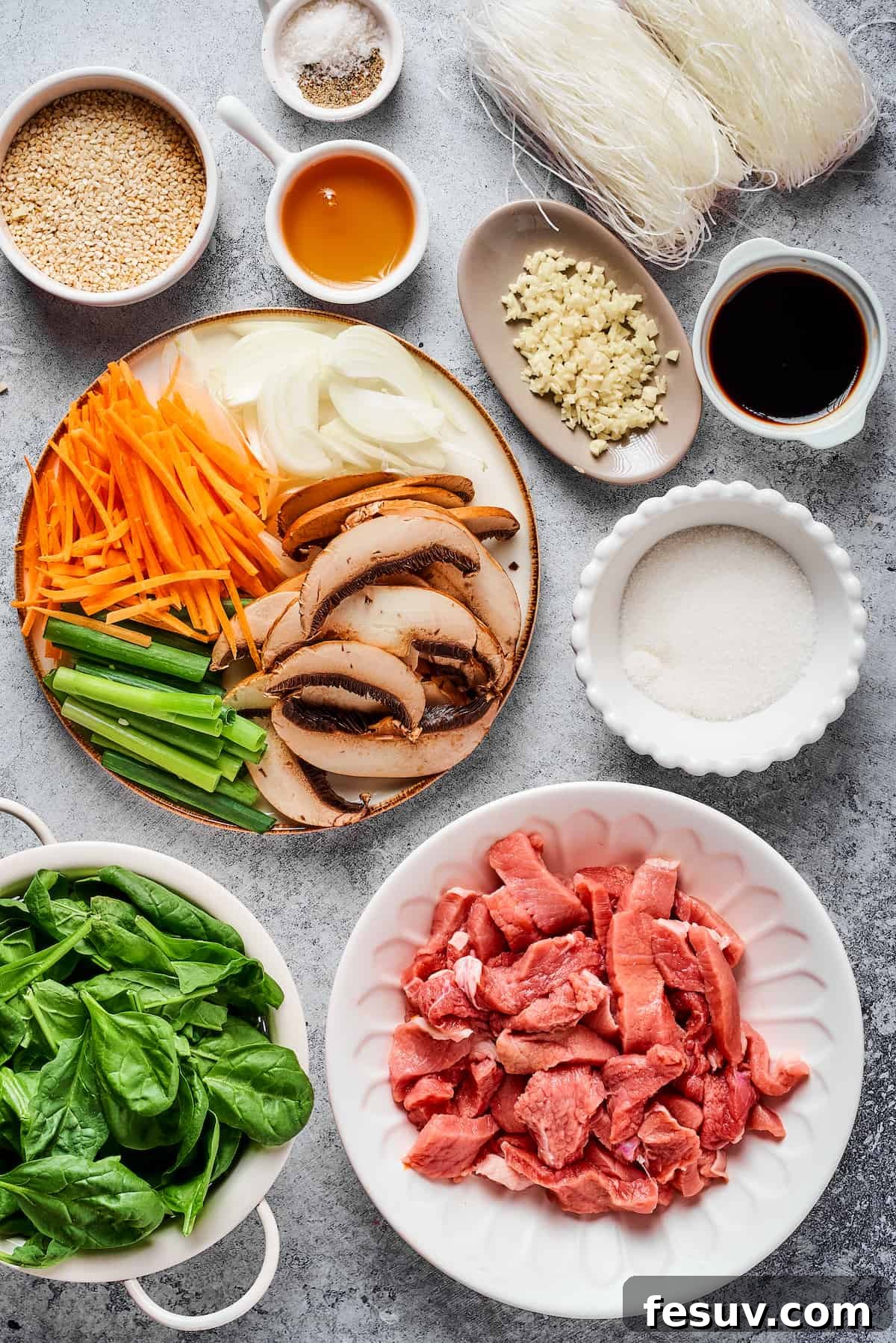 From top left: Toasted sesame seeds, salt and pepper, dried glass noodles, sesame oil, garlic, soy sauce, carrots, onions, green onion, mushrooms, sugar, spinach, sliced steak.