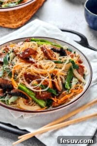 Japchae (Korean glass noodle stir fry) in a serving bowl, with chopsticks.
