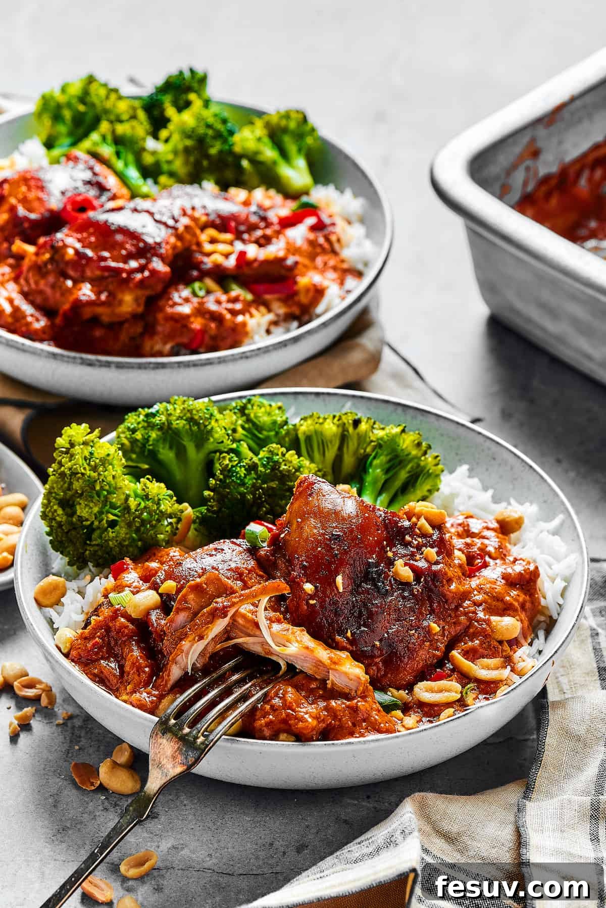 Simple Peanut Butter Chicken with crushed tomatoes, soy sauce, and garlic is a breeze to make. Serve this saucy chicken over rice, noodles, or cauliflower rice, and watch it disappear! Two plates of saucy chicken and veggies.