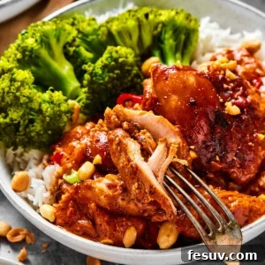 A close-up shot of a chicken thigh cooked in peanut sauce, with a fork pulling away a bite.