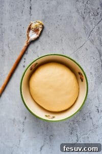 A smooth ball of dough in a large ceramic bowl.