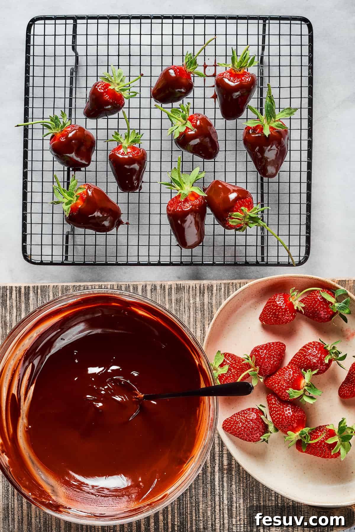Dipping Process for Chocolate Covered Strawberries A vibrant scene featuring fresh strawberries, a bowl of luxuriously melted chocolate, and a wire cooling rack holding several freshly dipped chocolate-covered strawberries, allowing them to set beautifully.
