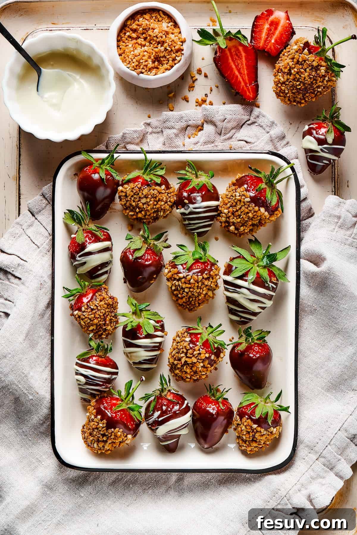 Beautifully Presented Chocolate Covered Strawberries A stunning arrangement of chocolate-covered strawberries presented on a decorative tray with a patterned cloth dishtowel. A small bowl of white chocolate sits nearby, suggesting the artisanal touch.