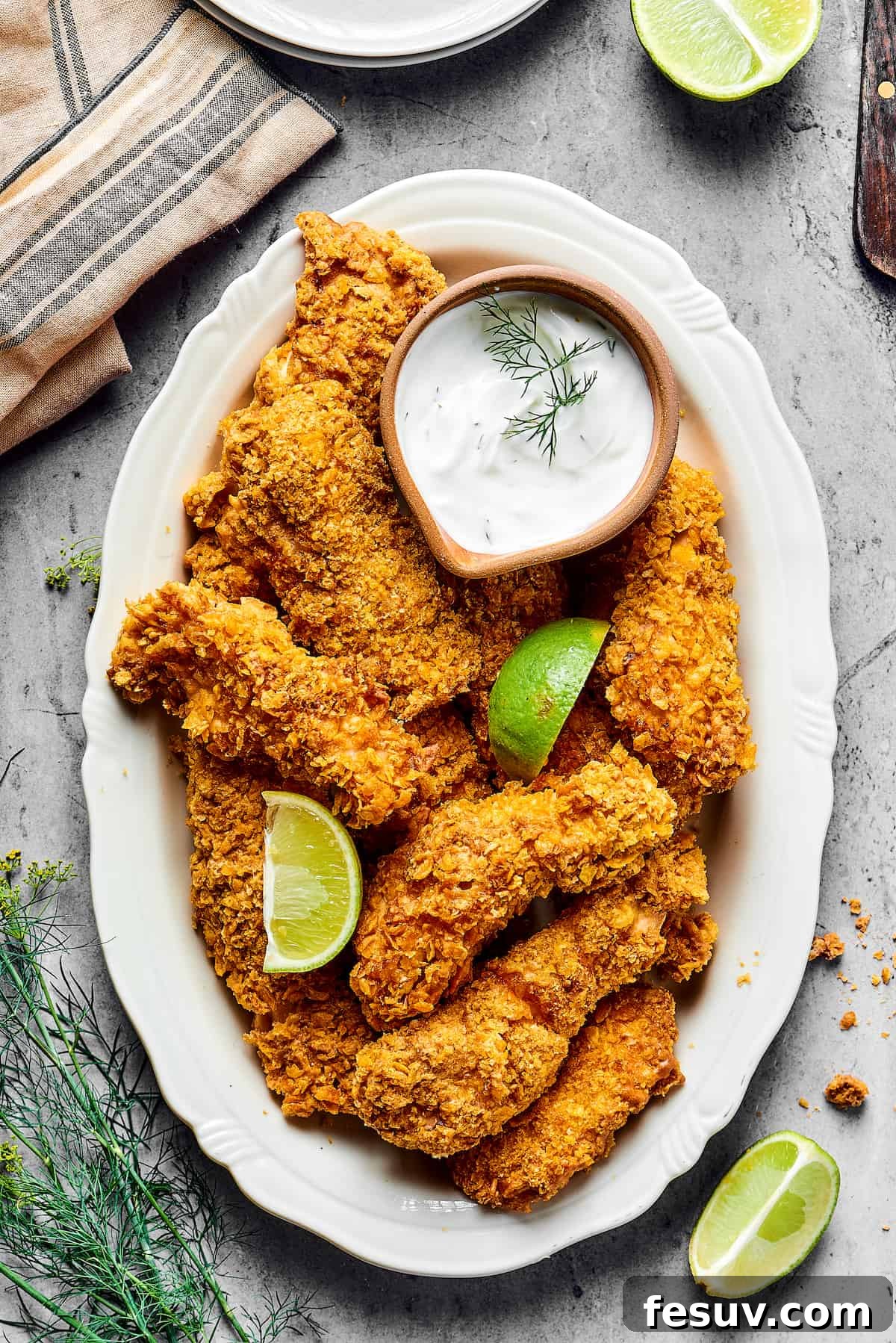 Air-fried chicken tempura pieces beautifully arranged on a platter, garnished with fresh lime wedges and a small bowl of dipping sauce.