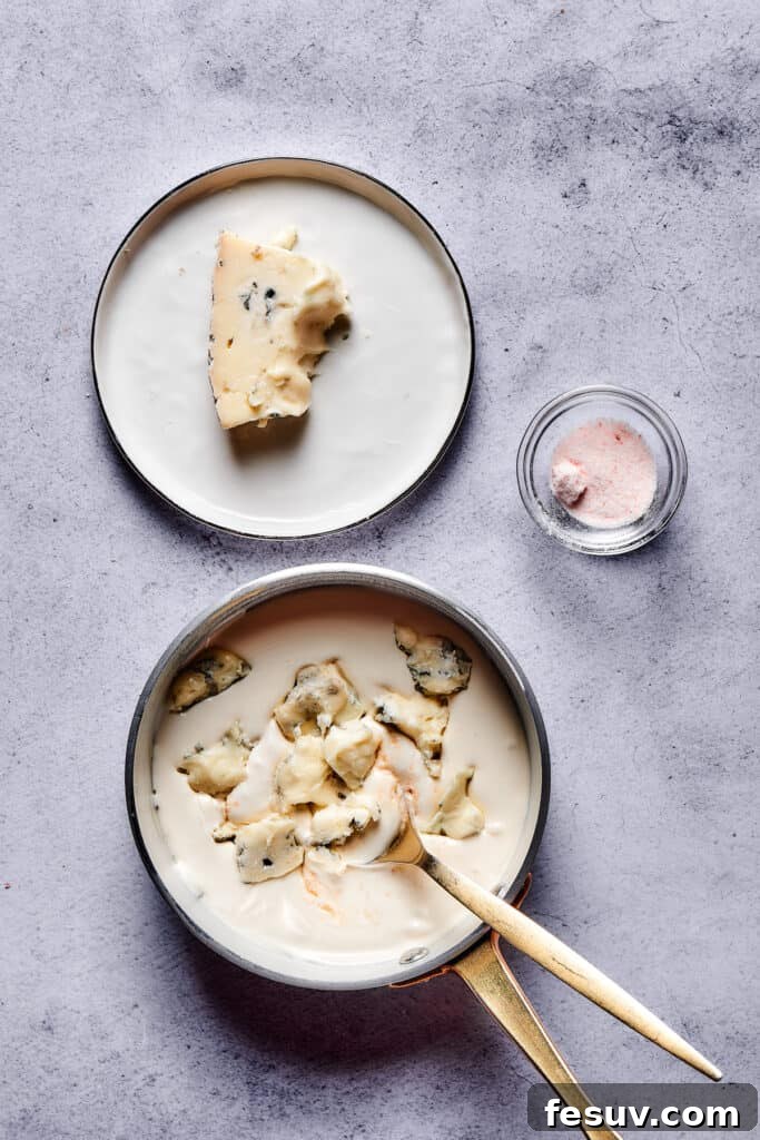 Rustic ceramic bowl overflowing with a rich, creamy blue cheese sauce, generously garnished with fresh herbs and a crumble of Gorgonzola cheese.
