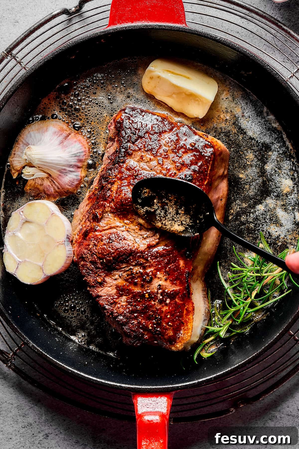 A chef's hand skillfully basting a sizzling blue steak with aromatic pan juices, enriched with butter and herbs, as it cooks in a cast-iron skillet, creating a perfect crust.