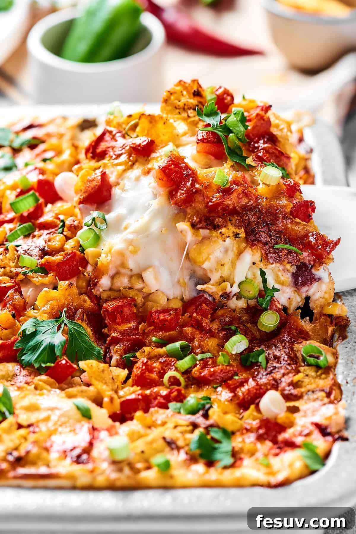 Fiesta Chicken Casserole 4 Close-up shot of a portion of Mexican chicken casserole being lifted out of a baking dish, showing the cheesy layers.