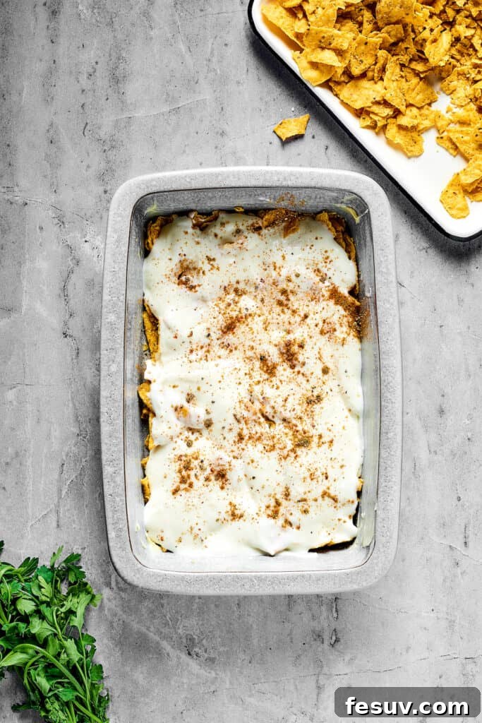Fiesta Chicken Casserole 6 A baking dish showing a layer of white sauce, chips, and seasoning at the bottom.