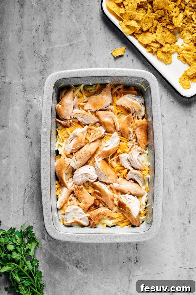 Fiesta Chicken Casserole 7 Layers of cheese and chicken over other ingredients in a baking dish.
