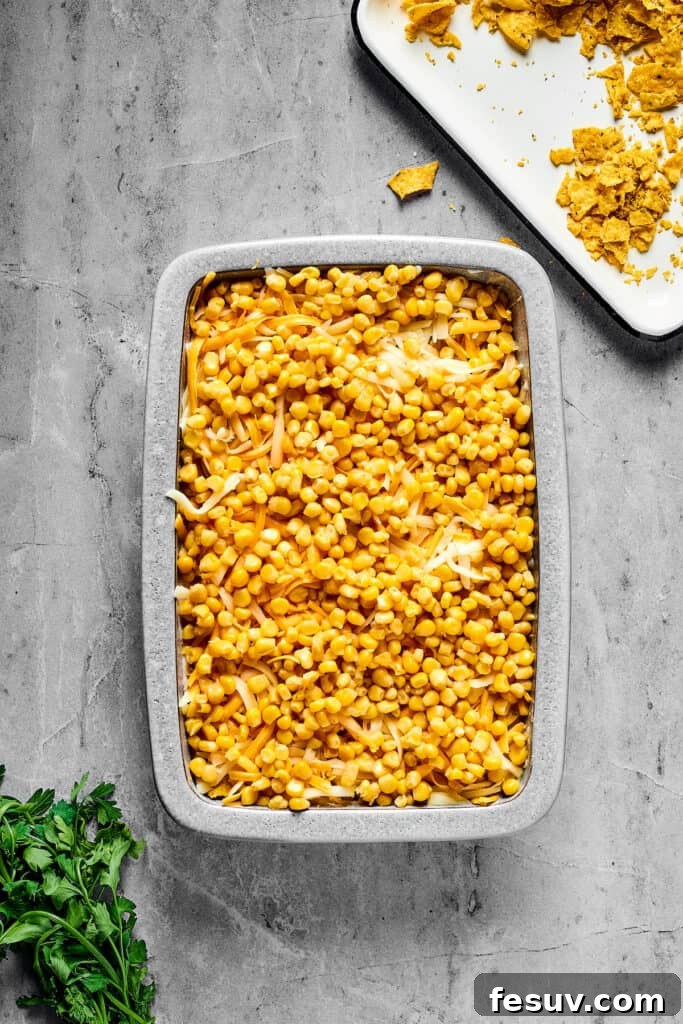 Fiesta Chicken Casserole 9 A baking pan with distinct layers of ingredients, with corn visible as a top layer before baking.
