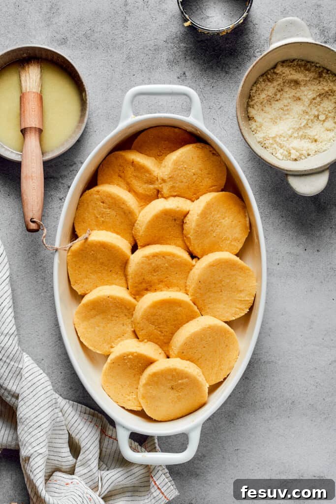 Circular semolina gnocchi artfully layered into an oval baking dish, ready for baking.