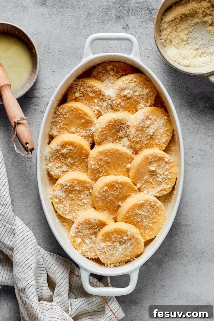 An oval baking dish of gnocchi elegantly dusted with Parmesan cheese, pre-baking.