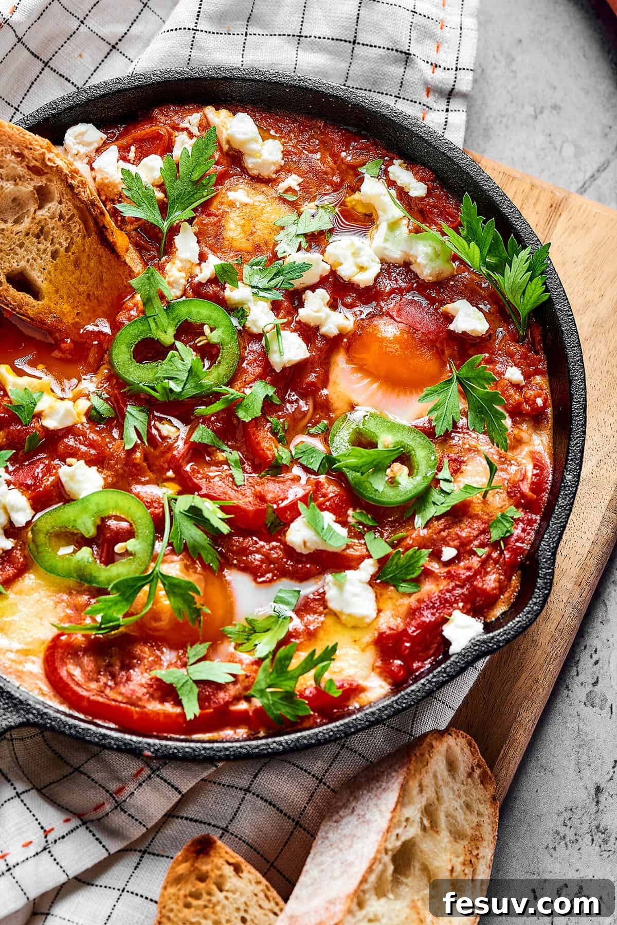 The Ultimate Shakshuka 5 Overhead shot of shakshuka in a cast-iron skillet, with toasted baguette.