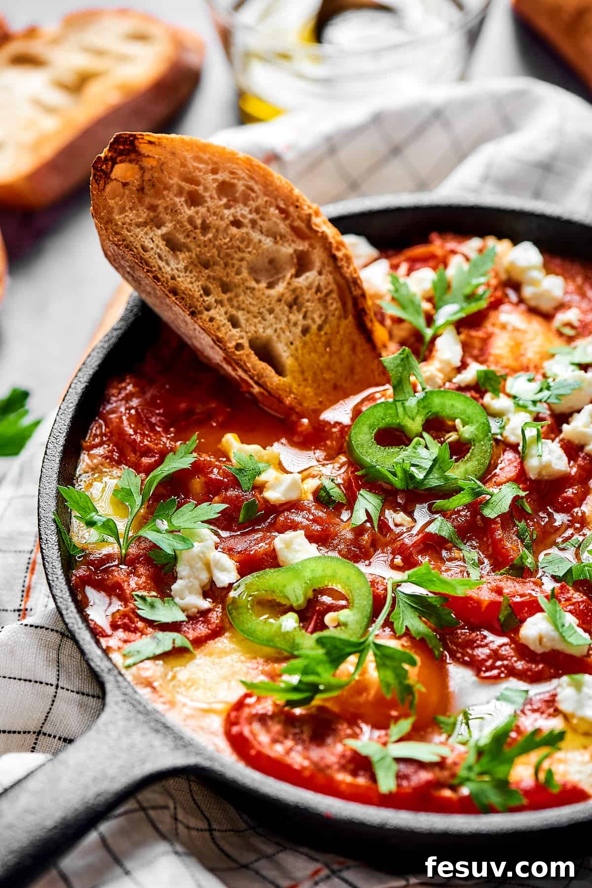 The Ultimate Shakshuka 10 A slice of toasted bread dipped in chunky tomato sauce and poached eggs, garnished with jalapeno and feta cheese.