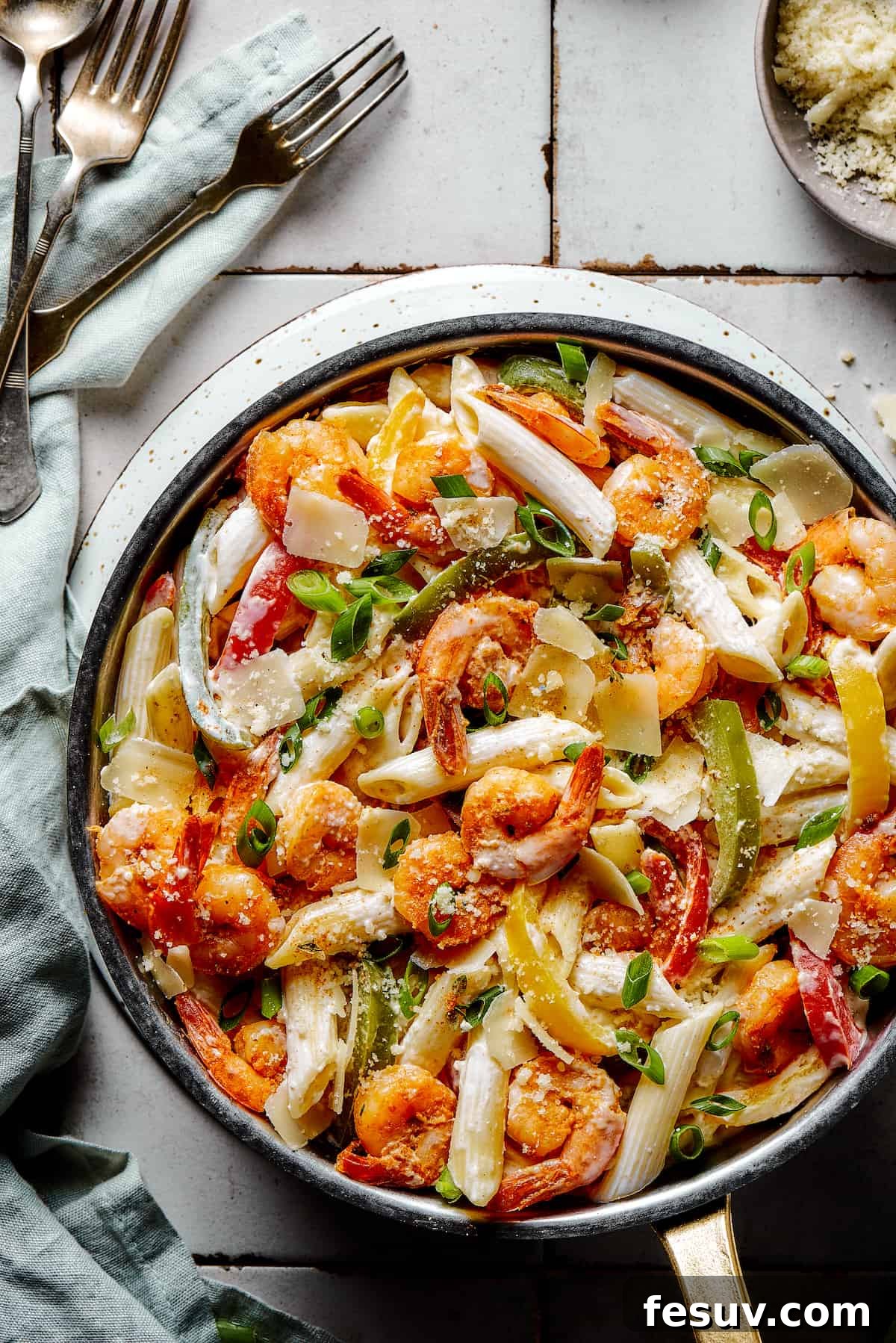 A skillet of Rasta pasta on a countertop, showcasing its creamy texture, perfectly cooked shrimp, and vibrant bell peppers.