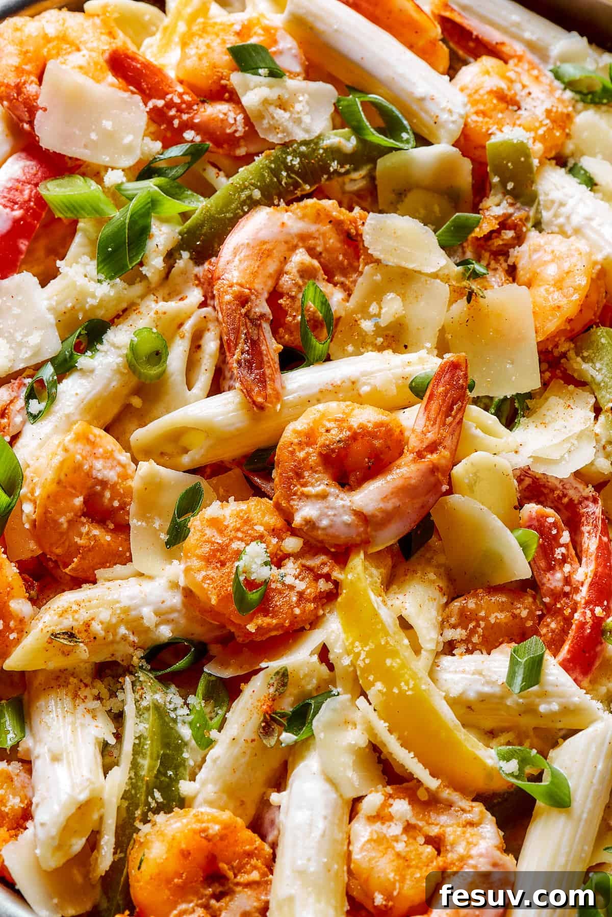 Close-up shot of Rasta pasta, highlighting the creamy sauce, plump shrimp, and vibrant bell pepper pieces, showcasing the dish's rich texture and color.