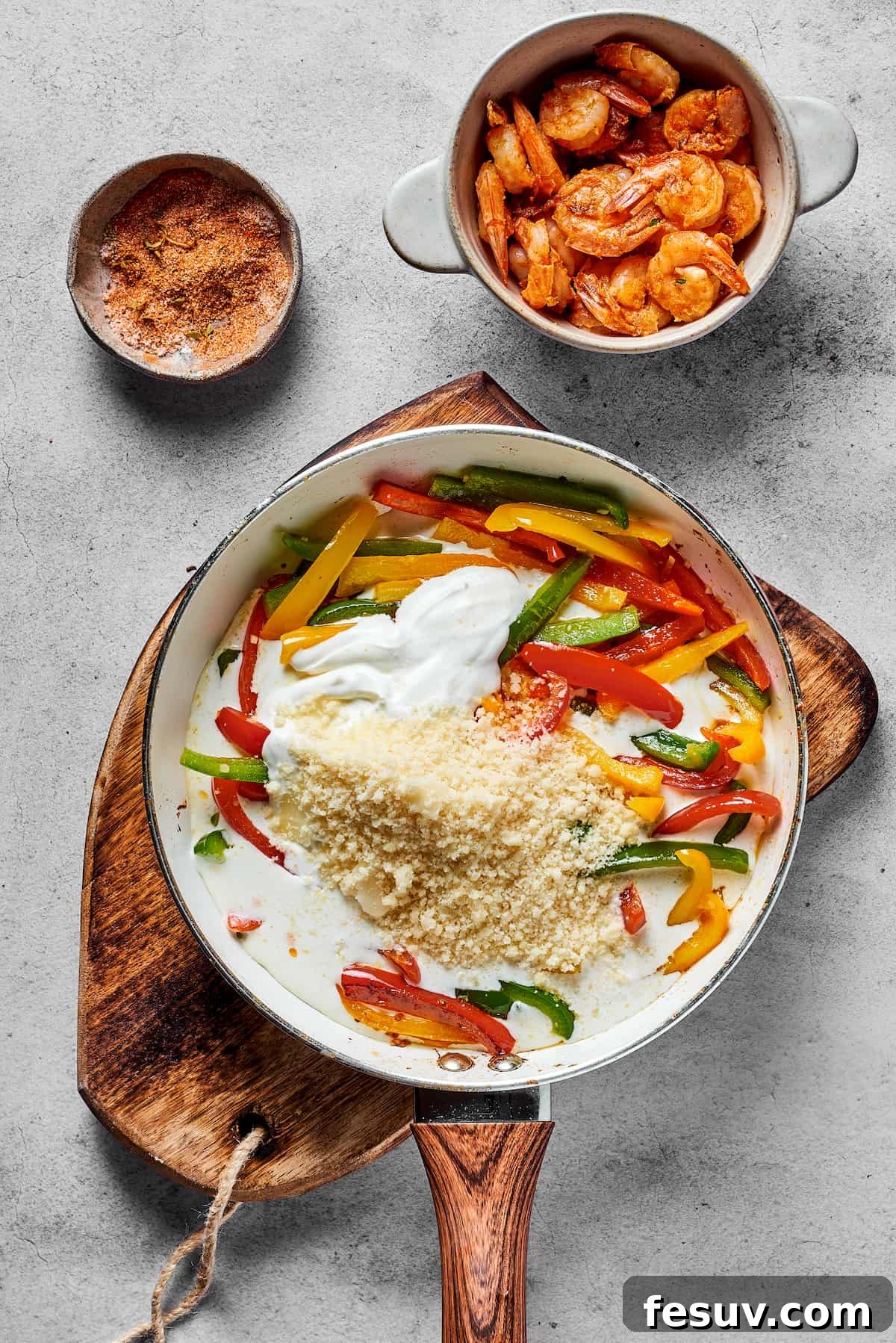 Bell peppers, grated Parmesan cheese, rich heavy cream, and softened cream cheese being stirred together in a skillet, forming a smooth and decadent creamy sauce.