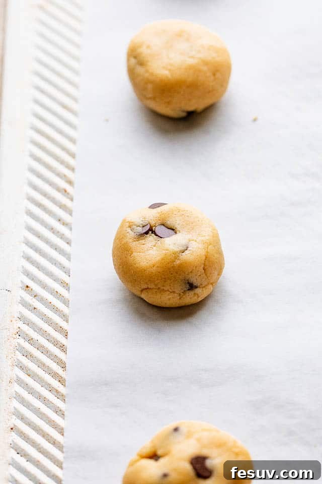 Carefully rolling portions of chocolate chip cookie dough into uniform balls by hand, ready for chilling and baking.