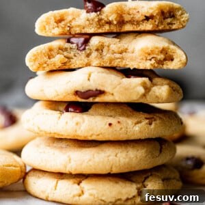 A small stack of perfectly baked, rich, and thick chewy chocolate chip cookies with melted chocolate.