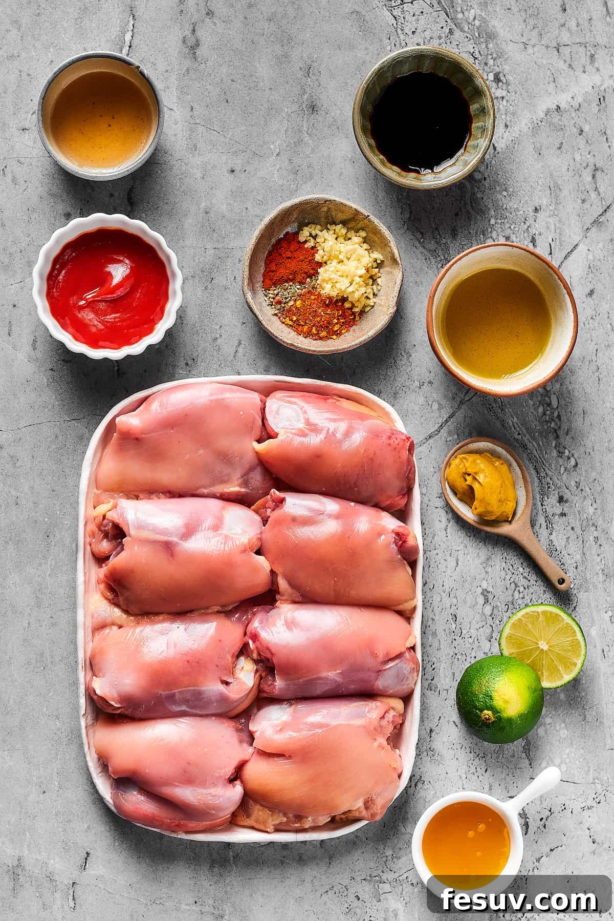 A flat lay photograph showcasing all the marinade ingredients: olive oil, soy sauce, ketchup, various seasonings, honey, Dijon mustard, lime, rice vinegar, neatly arranged around raw chicken thighs.